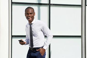 Fototapeta premium handsome african american businessman walking with mobile phone in city