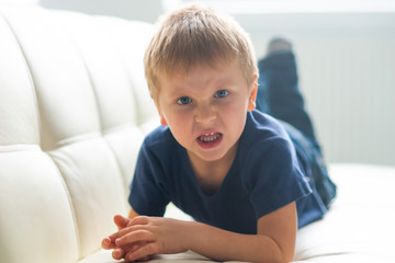 Fototapeta premium Portrait of hysterical boy. Upset caucasian kid crying at home.