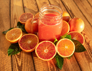 Bright composition with red oranges and fruit juice of fresh blood oranges, outdoor shot in the...