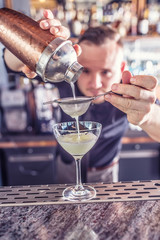 Professional barman making cocktail drink and pouring alcohol