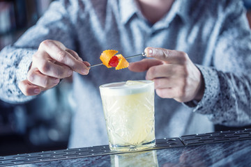 Professional barman making cocktail drink and decorated with fruits.