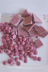 Broken and shattered pieces of ruby red chocolate in a round charcoal stone ceramic bowl.
