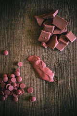Broken and shattered pieces of ruby red chocolate in a round charcoal stone ceramic bowl.