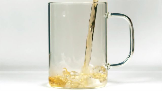 Pouring hot black tea into a glass mug, close-up slow motion shot