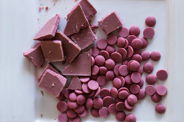Broken and shattered pieces of ruby red chocolate in a round charcoal stone ceramic bowl.