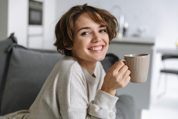 Happy young woman sitting on a couch at home