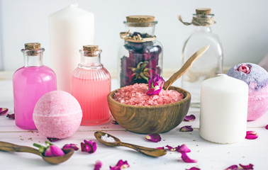 Cosmetics with rose oil. Bottles with liquid for the face, sea salt, candles, towels, bath foam, petals of dried roses.