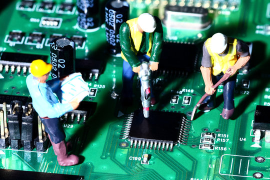 Conceptual diorama image of miniature figure workmen on an electronic circuit board