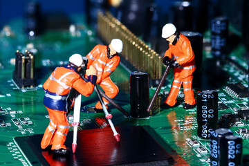 Conceptual diorama image of miniature figure workmen on an electronic circuit board