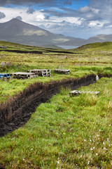 Trench cut into deep Peat of wetland moors near Drinan on Isle of Skye Scotland with Loch Slap and Beinn Na Caillich mountain peak