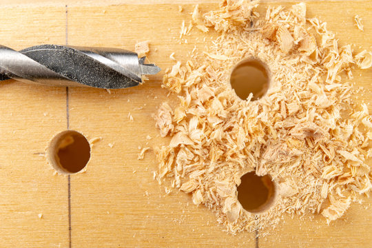 Drilling a hole in wood. Wood drill and plywood in a carpentry workshop.