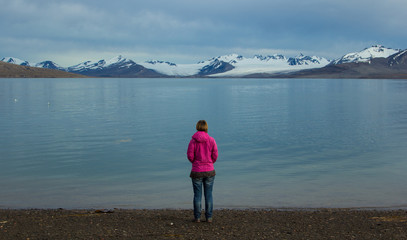 Fototapeta na wymiar A girl stands on the shores of the Greenland Sea