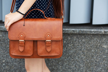 Street fashion concept. Woman holding brown leather briefcase. Copy space