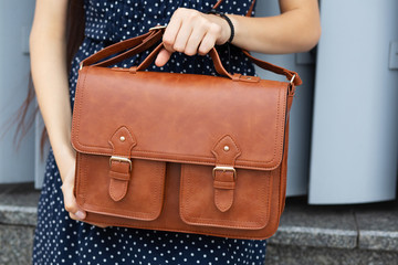 Street fashion concept. Woman holding brown leather briefcase. Space for text