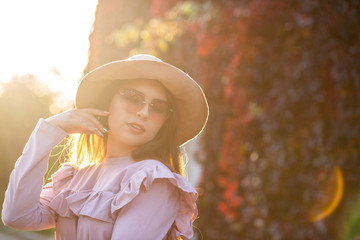 Gorgeous tanned girl wearing trendy hat and sunglasses, posing outdoor with sun rays. Empty space