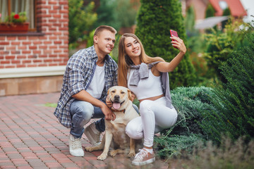 Happy moments together! Young beautiful couple with dog taking a selfie.