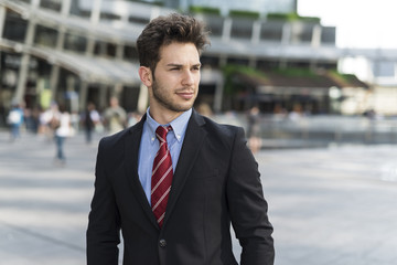 Portrait of a young handsome businessman walking in a city