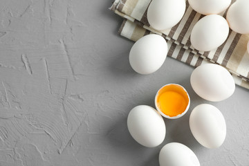 Chicken eggs in kitchen towel on gray background, space for text