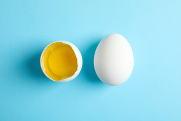 Chicken egg and half with yolk on color  background, space for text