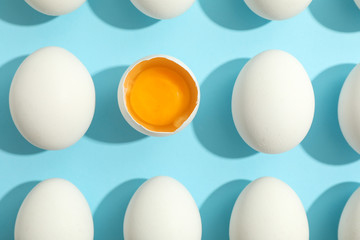 Flat lay composition with chicken eggs and half with yolk on color background, space for text
