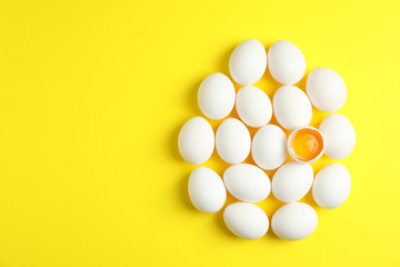 Flat lay composition with chicken eggs and half with yolk on color background, space for text