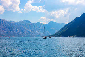Incredible bright seascape. View of green wooded mountains and blue sea, blue sky and white clouds. Boka Kotorska Bay, Montenegro