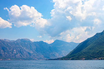 Incredible bright seascape. View of green wooded mountains and blue sea, blue sky and white clouds. Boka Kotorska Bay, Montenegro