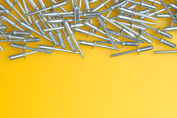Rivets. f lot of rivets ion yellow background. Top view. Falling rivets. Copy space for text.