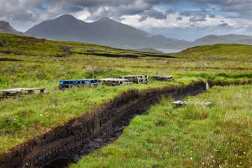 Trenches cut into deep Peat of wetland moors near Drinan on Isle of Skye Scotland with Loch Slap and Beinn Dearg Mhor and Beinn Na Caillich peaks
