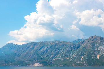 Incredible bright seascape. View of green wooded mountains and blue sea, blue sky and white clouds. Boka Kotorska Bay, Montenegro