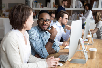 African male caucasian female talking sitting at desk near pc