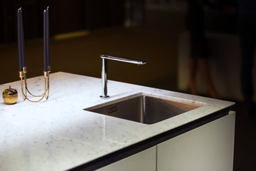 Modern kitchen, the water tap and kitchen sink. Kitchen island with a tap and marble white worktop