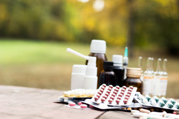 Medicines on wooden table, nature bokeh background