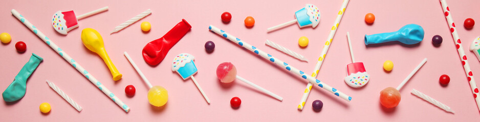 Flat lay childs birthday party, pink background (pattern). Sweet candies, bright balloon, festive candles, cupcake and straws.