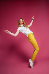 Good Party Mockup. Cheerful blonde woman in white headphones, white T-shirt and trendy yellow jeans...