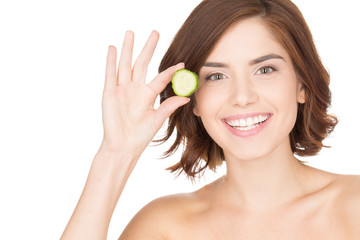 Healthy looks come from the inside. Closeup of a beautiful girl holding a slice of cucumber to her face and smiling cheerfully