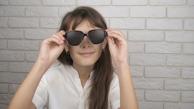 Eyeglasses for vision correction. The little girl takes off and shows the obscura glasses.