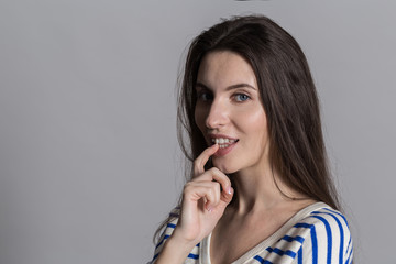 Pretty woman with fluffy hair, dressed casually against a gray studio wall