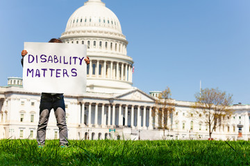 Protester boy holding sign disability matters hiding face