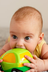 The baby boy is playing with a green little car