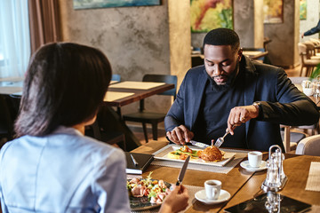 The team that eats together, stays together. Two colleagues having lunch in company's restaurant. Focus on the man