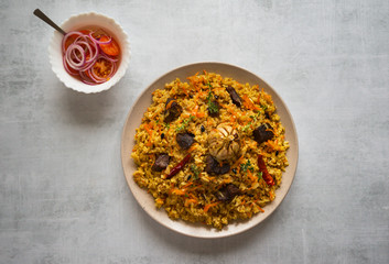 Uzbek pilaf in a plate on a white wooden table. 