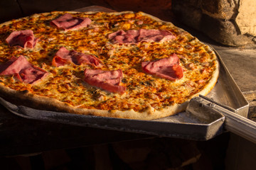 Baked pizza on the shovel in a stone oven.