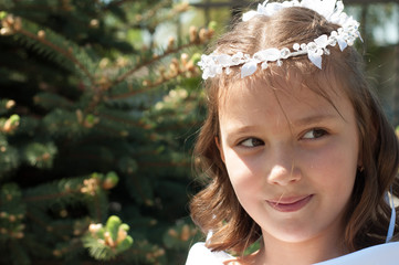 Portrait of cute little girl on white dress and wreath of first holy communion