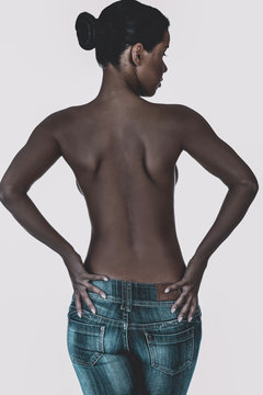 Back view of african black woman in blue jeans, on white background.