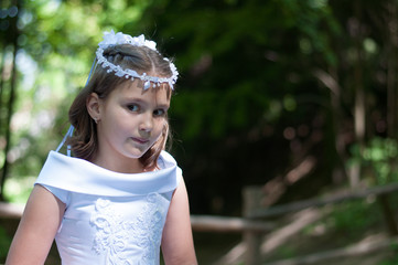 Portrait of cute little girl on white dress and wreath of first holy communion