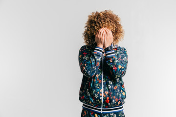 Unrecognizable man in modern tracksuit with flowers hidng  face with hands. Indoor emotional...
