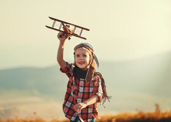 Child pilot aviator with airplane dreams of traveling in summer  at sunset