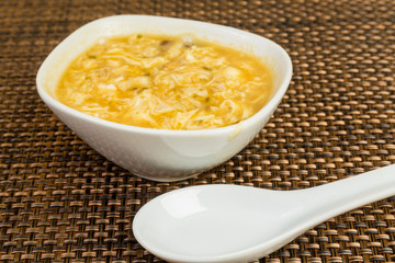 Bowl of Hot and Sour Soup on Straw Mat with Oriental Soup Spoon