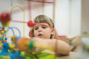 Cute little girl playing with abacus at kindergarten